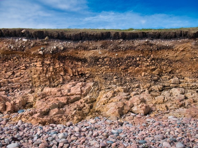 Eroding soil, subsoil and bedrock at a pebble beach in, Shetland, UK. Image: Getty/Alan Morris